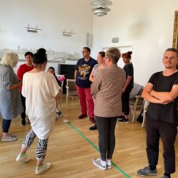 Eine Gruppe von Menschen steht in einem Raum und unterhält sich lebhaft in lockerer Anordnung.