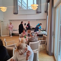 Menschen genießen ein Buffet in einem hellen, modern eingerichteten Raum mit großen Fenstern und stilvollen Lampen.