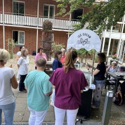 Menschen stehen in einer Schlange an einem Eisstand vor einem Backsteingebäude, um draußen Eiscreme zu genießen.