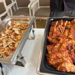 Zwei Tabletts mit bunten Gemüse- und würzigen Peperoni-Pizzastücken stehen einladend auf einem Tisch bereit.