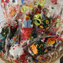 Ein Korb voller bunter Geschenkpakete mit Weihnachtsmotiven und Schleifen sorgt für festliche Stimmung.