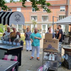 Eine Gruppe von Menschen genießt Eis vor einem kunstvollen Brunnen neben einem charmanten Eiskiosk im Freien.