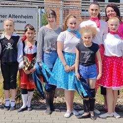 Eine Gruppe von Mädchen in bunten Kostümen posiert fröhlich vor dem Posener Altenheim für ihren Aerobic-Auftritt im Mai.