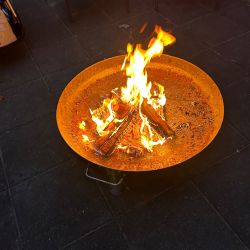 Ein lebhaftes Feuer brennt in einer großen Metallschale auf der Terrasse, umgeben von einladenden Stühlen.