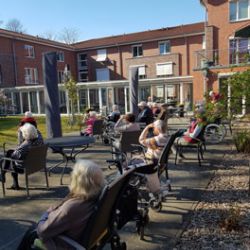 Senioren entspannen an einem sonnigen Frühlingsnachmittag im Innenhof einer Wohnanlage.