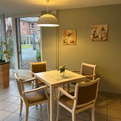 Ein gemütlicher Essbereich mit Tisch, vier Stühlen und Blumendekoration ist von einer Hängelampe warm beleuchtet.