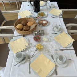 Ein festlich gedeckter Tisch mit Brötchenkorb, Aufschnitt und Kaffeekanne lädt zum gemütlichen Frühstück ein.