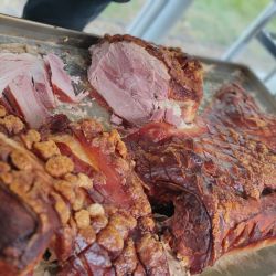 Knusprig gebratenes Fleisch liegt appetitlich auf einem Tablett, bereit zum Servieren beim Buffet neben gestapelten Tellern.