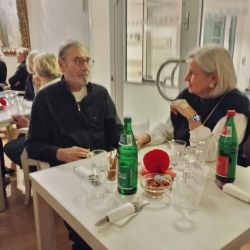 Ein älteres Paar sitzt in einem Café, genießt gemeinsam Getränke und Snacks und führt ein angeregtes Gespräch.