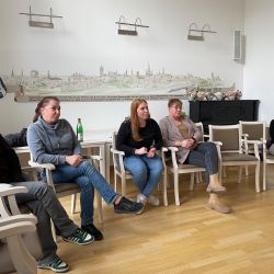 Mehrere Frauen sitzen in einem Raum auf Stühlen und hören aufmerksam einem Vortrag zu.