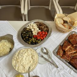 Eine vielseitige Auswahl an Antipasti, Brot und Pizza liegt auf einem Tisch mit weißen Tischdecken arrangiert.